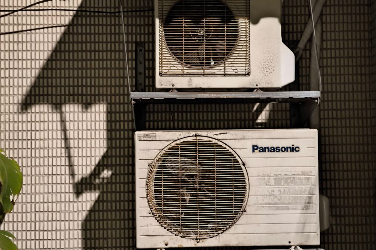 Two ductless mini split outdoor units mounted one above the other on a wall